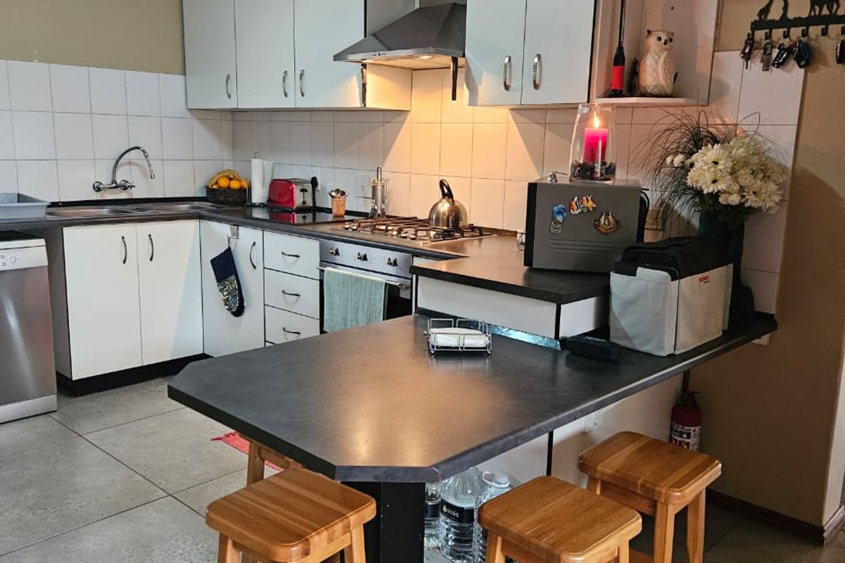 Functional kitchen featuring white cabinetry, a gas hob with extractor fan, tiled backsplash, and an integrated breakfast bar counter.