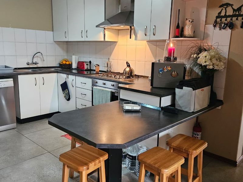 Functional kitchen featuring white cabinetry, a gas hob with extractor fan, tiled backsplash, and an integrated breakfast bar counter.