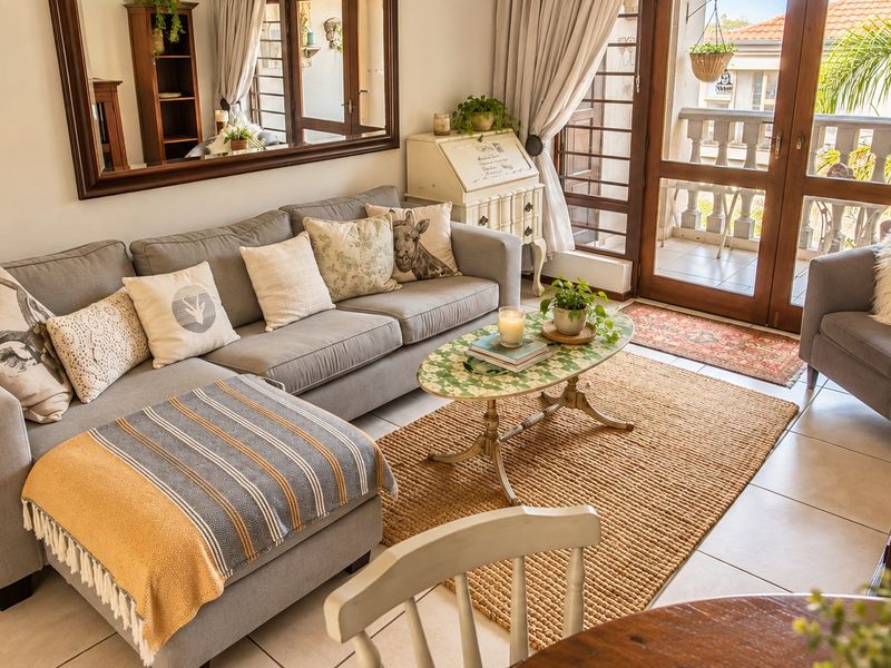 A bright and inviting living room featuring tiled flooring and direct access to a private balcony through double glass doors.