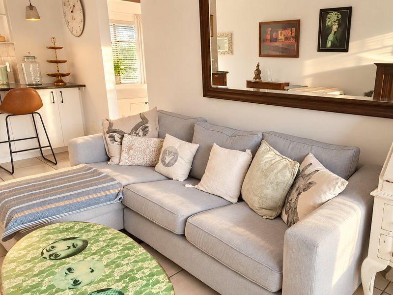 An open-plan living area featuring tiled flooring, a compact kitchen with granite countertops, and integrated cabinetry, creating a functional and connected living space.