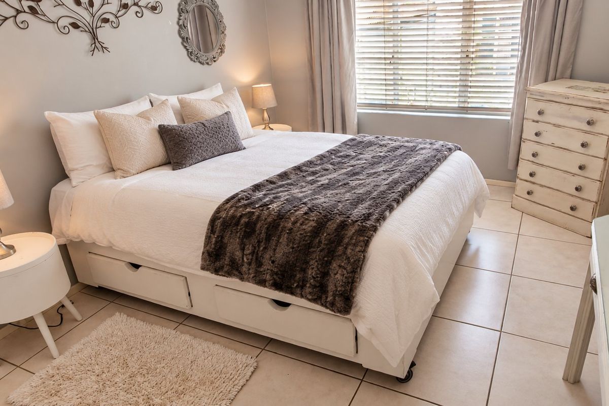 A well-maintained bedroom featuring neutral tiled flooring and venetian blinds, offering a clean and comfortable living space.