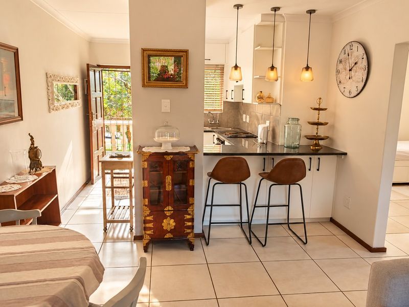 Open-plan living area featuring a functional kitchen with granite countertops, tiled flooring, and direct access to an outdoor balcony.