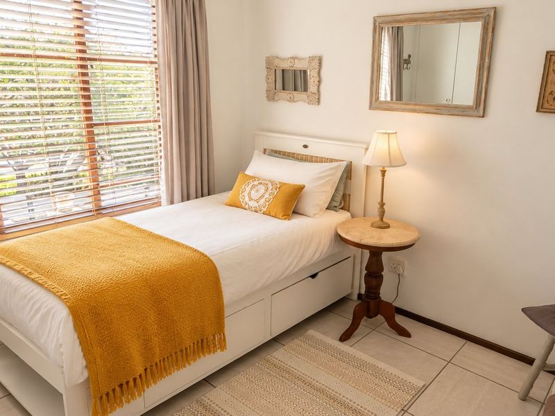 A bright and well-maintained bedroom featuring tiled flooring, large windows with venetian blinds, and neutral wall finishes.