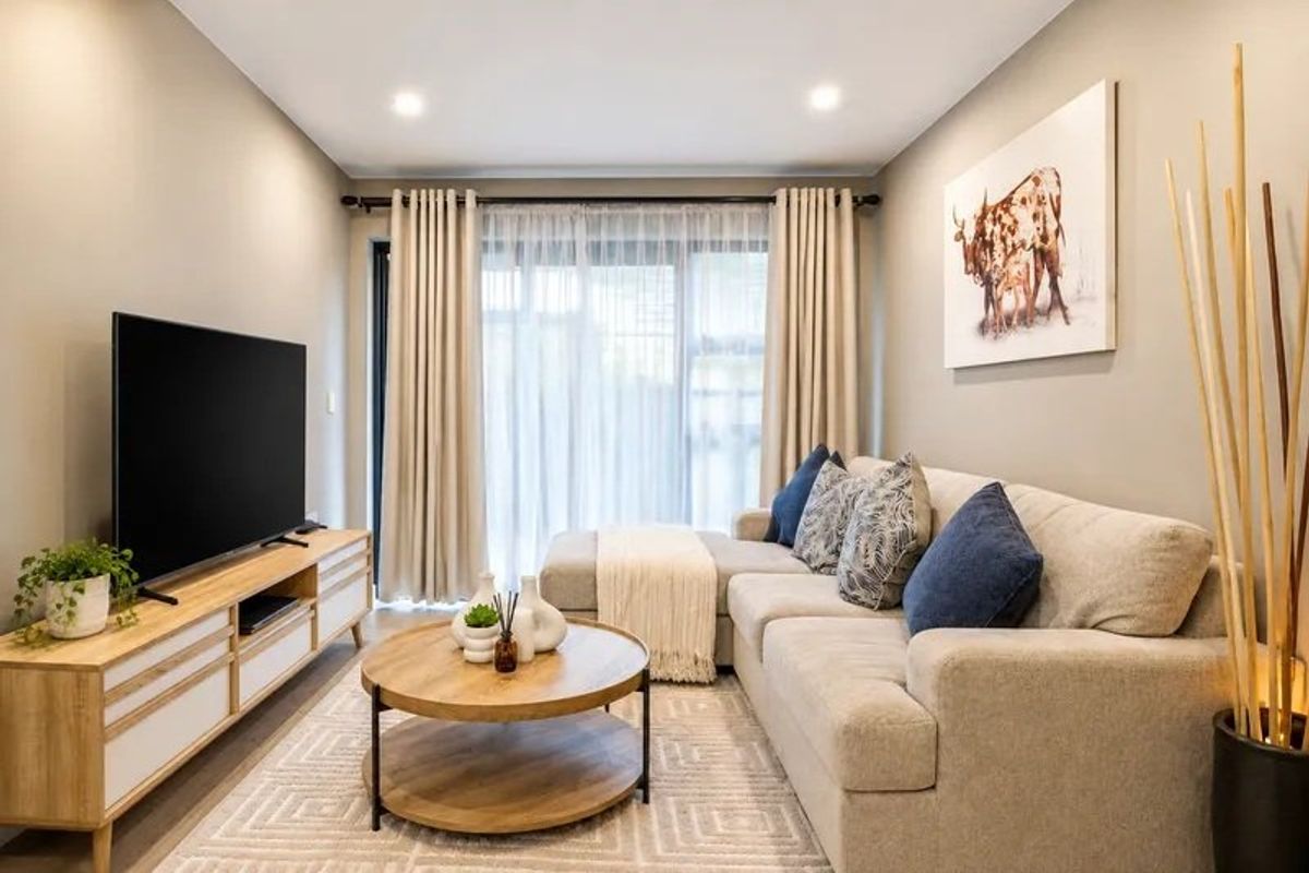 A well-maintained living room featuring neutral wall tones, recessed downlighting, and a large sliding glass door providing access to the exterior.