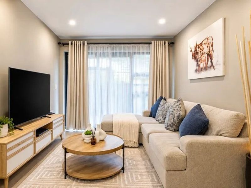 A well-maintained living room featuring neutral wall tones, recessed downlighting, and a large sliding glass door providing access to the exterior.