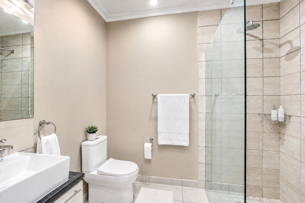 Modern bathroom featuring a glass-enclosed shower, contemporary vanity with stone countertop, and neutral wall finishes.