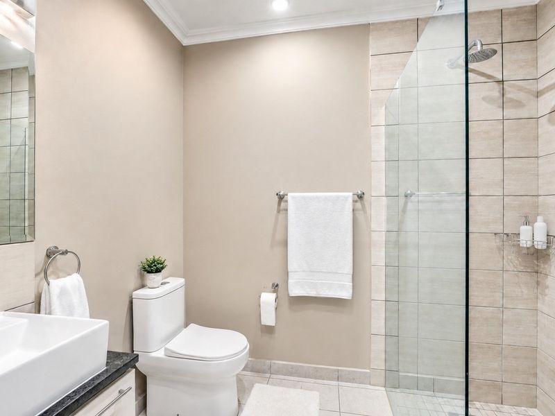 Modern bathroom featuring a glass-enclosed shower, contemporary vanity with stone countertop, and neutral wall finishes.