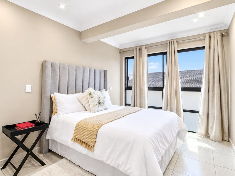A bright and well-maintained bedroom featuring tiled flooring, recessed downlighting, and large sliding windows that allow for ample natural light.