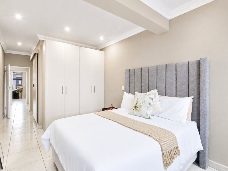 A well-maintained bedroom featuring neutral walls, tiled flooring, recessed downlighting, and ample built-in cupboard storage.