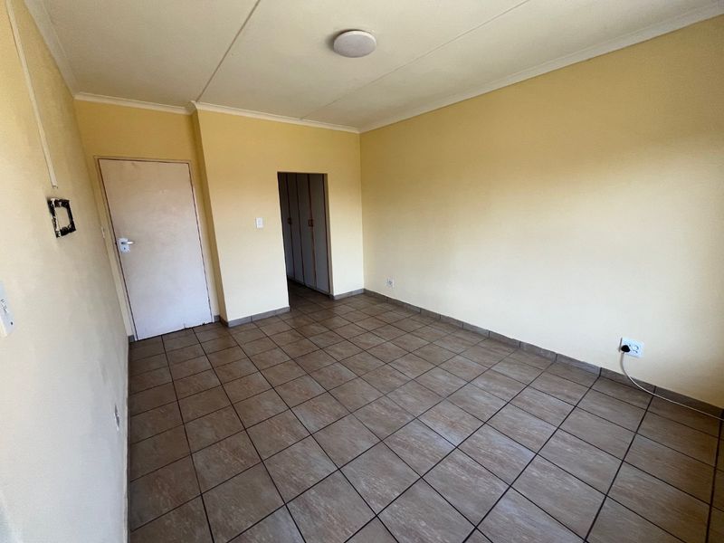An empty bedroom featuring tiled flooring, neutral wall paint, and built-in cupboard storage space.