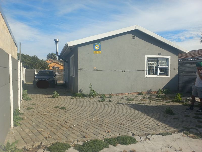Front exterior view of the house featuring a paved driveway, security bars on windows, and a precast concrete boundary wall.