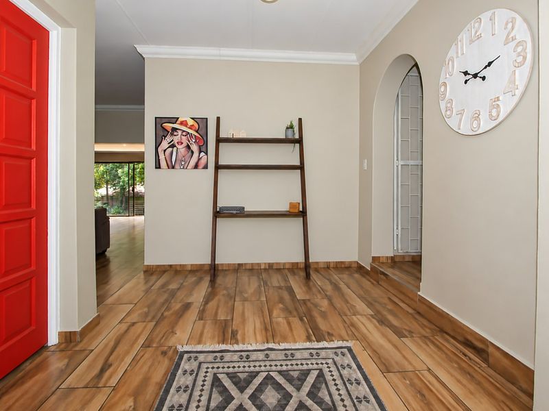 Welcoming entrance hall featuring wood-look tile flooring, a distinctive arched doorway, and a bright red accent door.