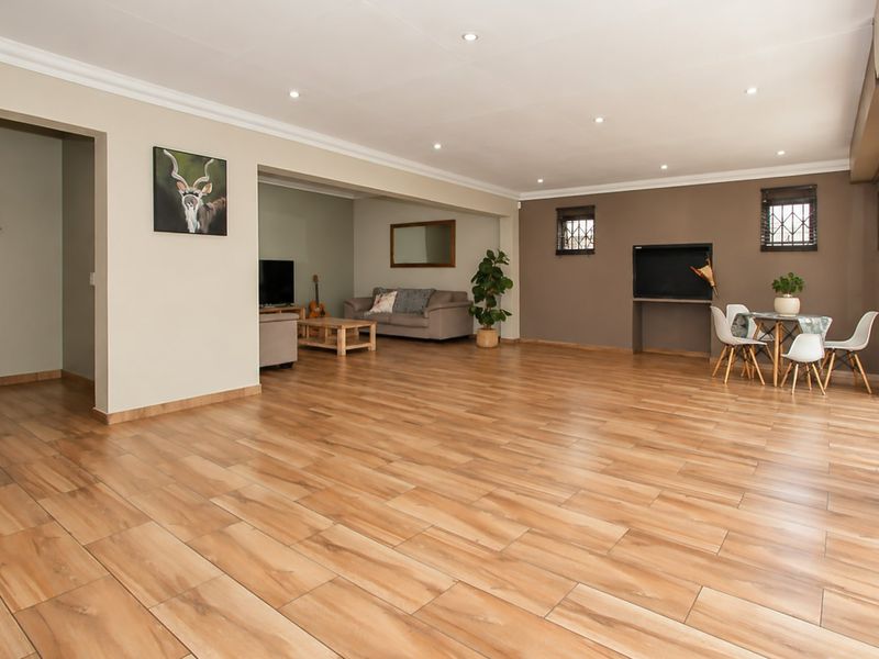Spacious open-plan living area featuring wood-look tile flooring, recessed downlights, and a built-in fireplace, with large sliding doors providing natural light.