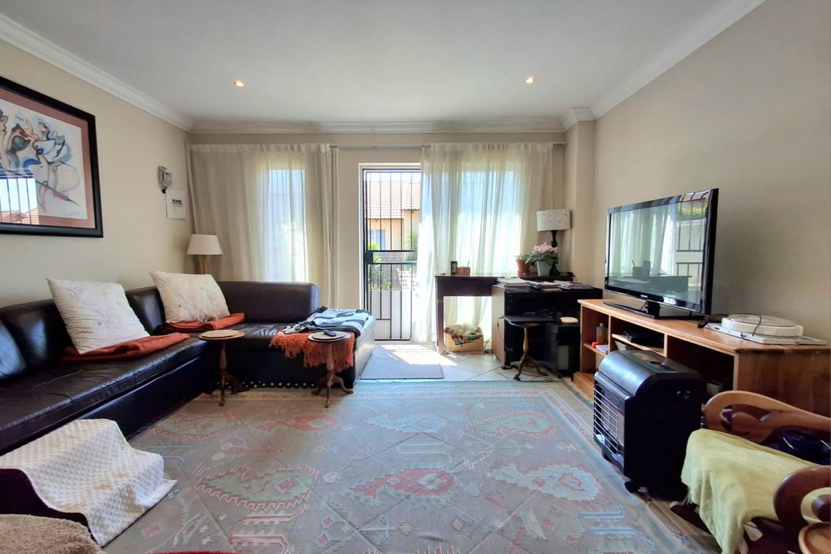 A comfortable living room featuring recessed downlighting, decorative cornicing, and a security gate leading to the exterior.