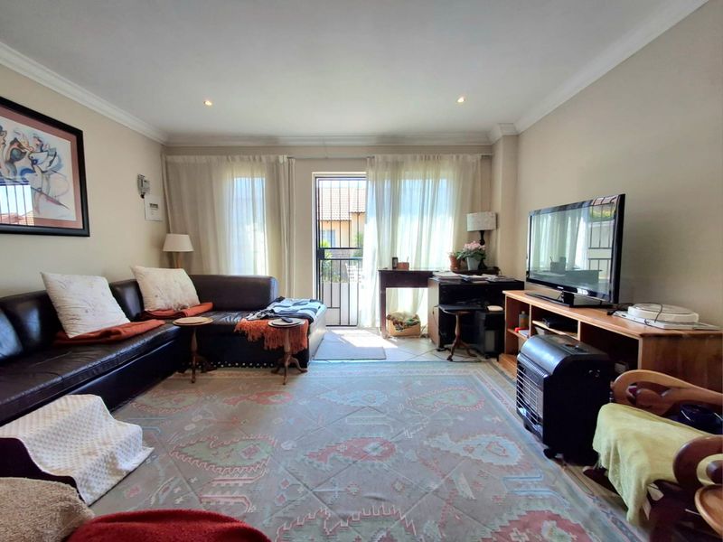 A comfortable living room featuring recessed downlighting, decorative cornicing, and a security gate leading to the exterior.