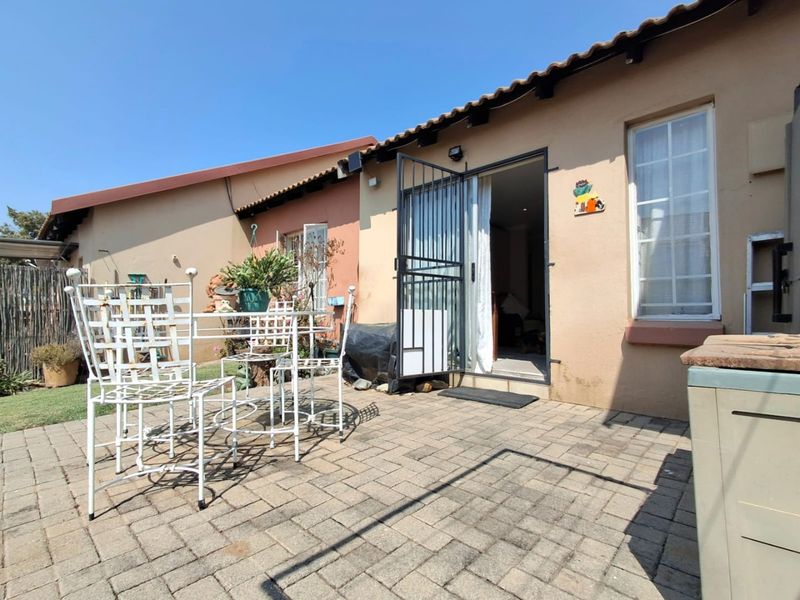 A paved outdoor patio area featuring a security gate entrance, providing a functional space for outdoor seating and access to the home interior.