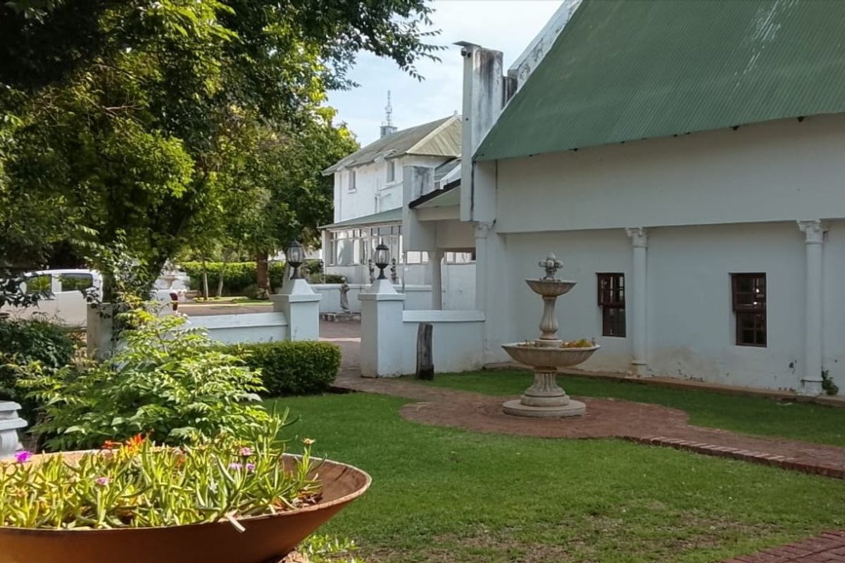 A well-maintained rear garden area featuring a central stone fountain, brick pathways, and established landscaping adjacent to the main building structure.