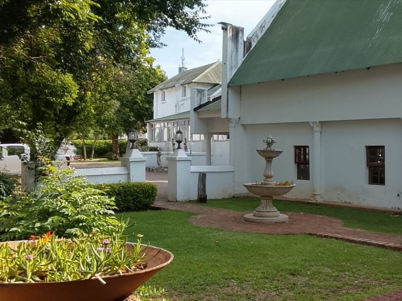 A well-maintained rear garden area featuring a central stone fountain, brick pathways, and established landscaping adjacent to the main building structure.