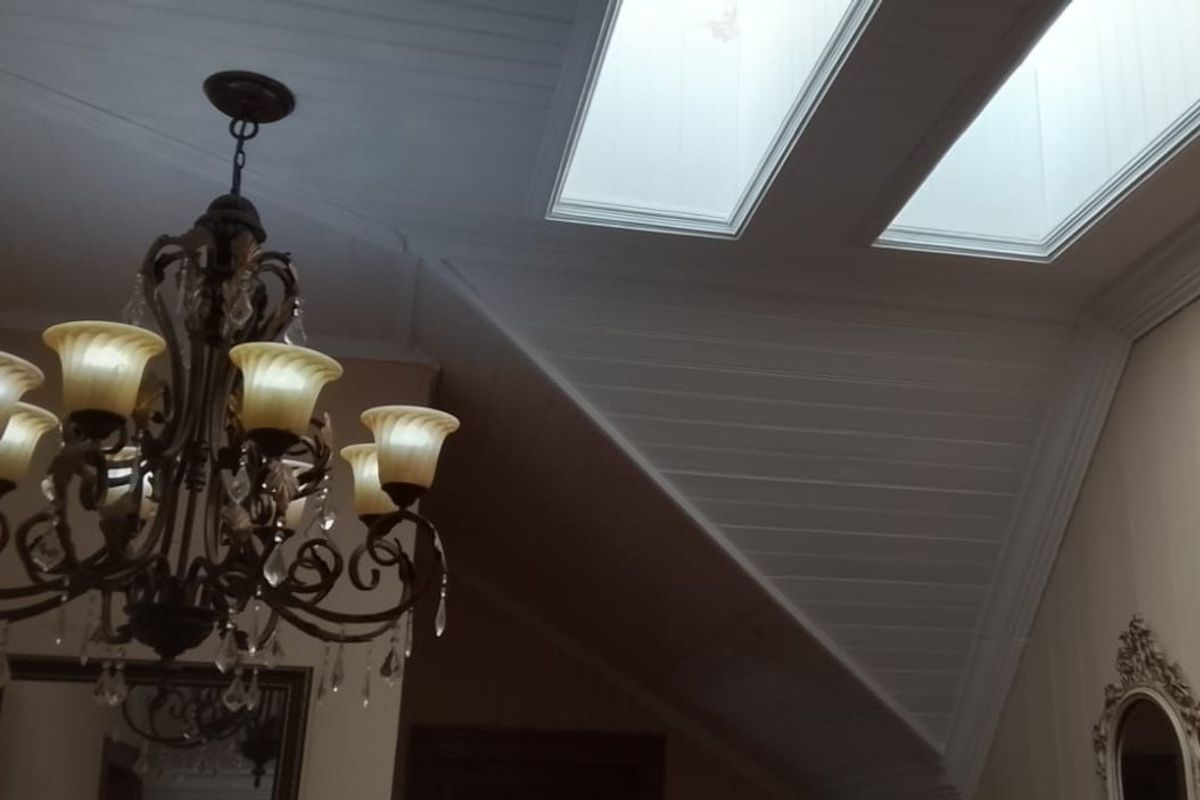 A well-maintained living area featuring a vaulted tongue and groove ceiling with dual skylights and an elegant ornate chandelier.