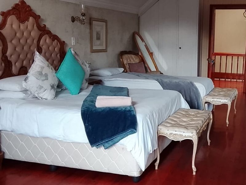 Spacious bedroom featuring polished hardwood flooring, built-in storage cupboards, and classic wall sconce lighting.