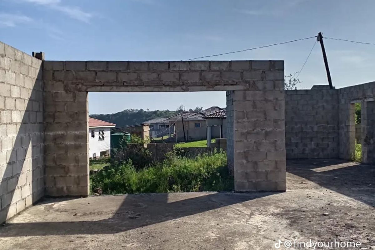 An unfinished construction site featuring exposed concrete block walls and a concrete slab floor, awaiting further development and finishing.