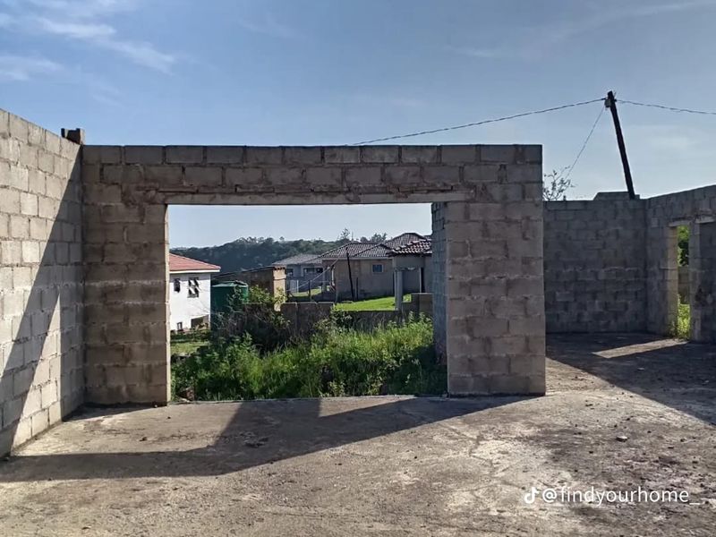 An unfinished construction site featuring exposed concrete block walls and a concrete slab floor, awaiting further development and finishing.