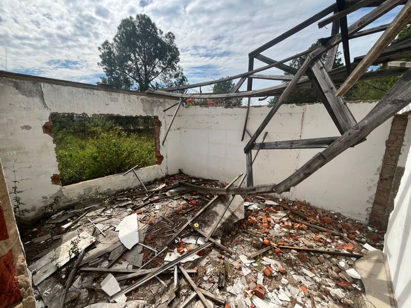 A severely dilapidated structure with a collapsed roof and missing wall sections, requiring significant reconstruction or demolition.