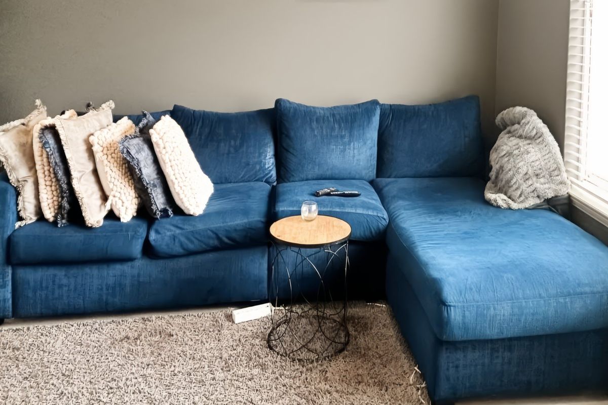 A cozy living room area featuring neutral wall tones and venetian blinds, providing a comfortable space for relaxation.