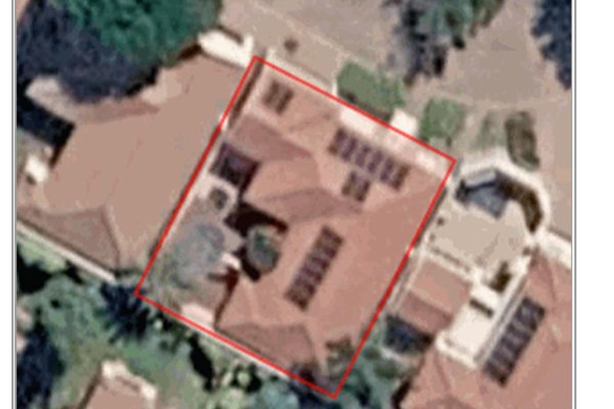 An aerial satellite view showing the property footprint, roof structure, and installed solar panels.
