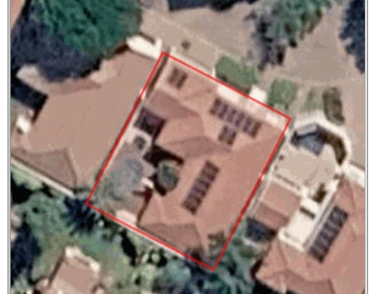 An aerial satellite view showing the property footprint, roof structure, and installed solar panels.