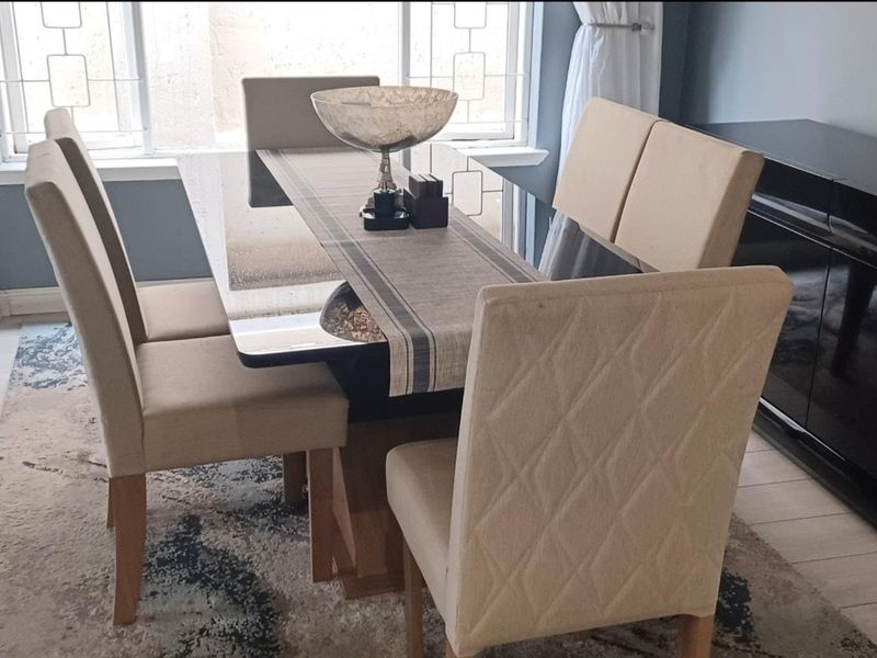 A well-lit dining room featuring large windows and neutral tiled flooring, providing a bright and functional space for meals.