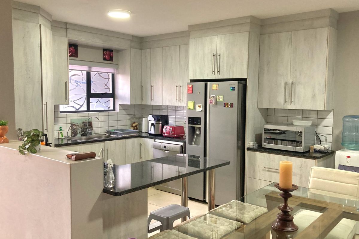 A functional kitchen featuring light-toned cabinetry, granite countertops, a subway tile backsplash, and a breakfast bar peninsula, providing ample storage and workspace.