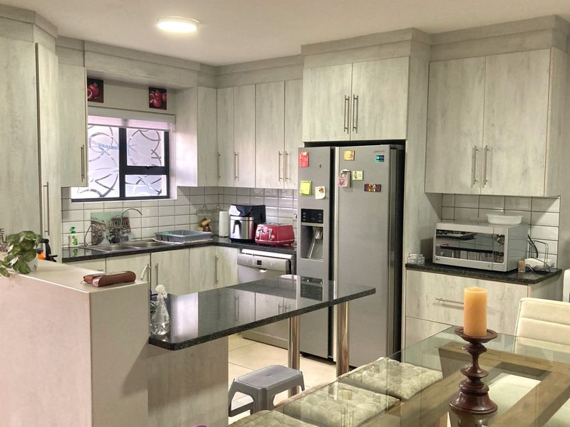 A functional kitchen featuring light-toned cabinetry, granite countertops, a subway tile backsplash, and a breakfast bar peninsula, providing ample storage and workspace.