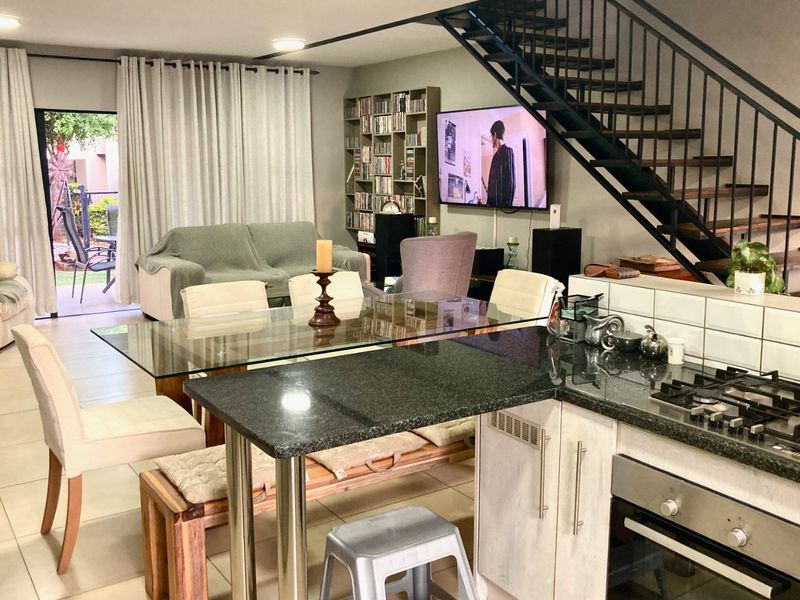 Open-plan living and dining area featuring a modern kitchen with granite countertops, gas cooktop, and a staircase leading to the upper level.