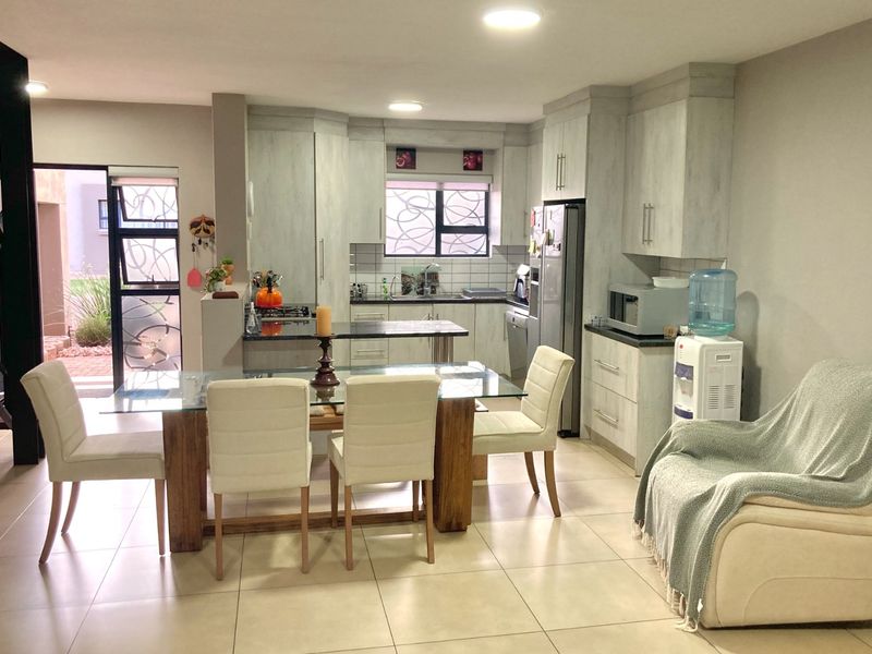 Open-plan kitchen and dining area featuring modern cabinetry, granite countertops, tiled flooring, and direct access to an outdoor patio space.