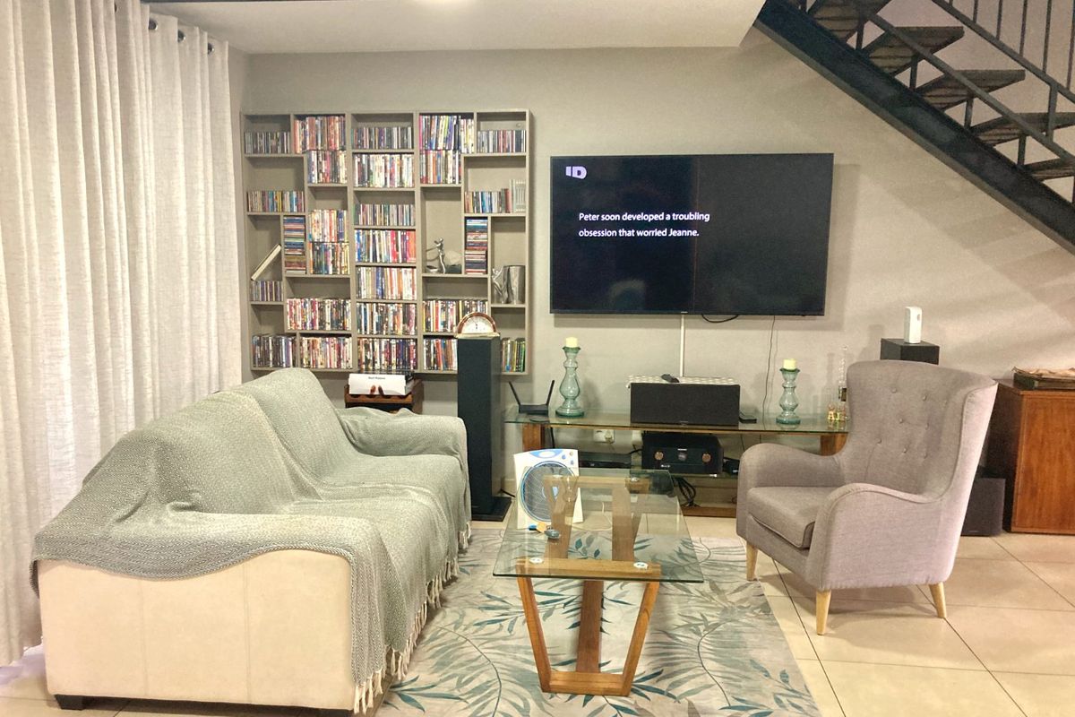 A comfortable living room featuring built-in shelving, tiled flooring, and an open staircase leading to the upper level.
