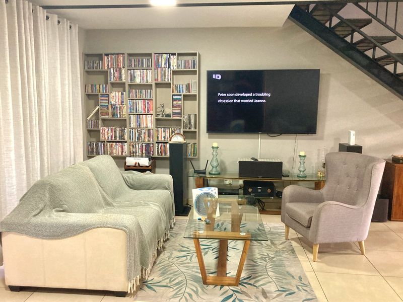 A comfortable living room featuring built-in shelving, tiled flooring, and an open staircase leading to the upper level.