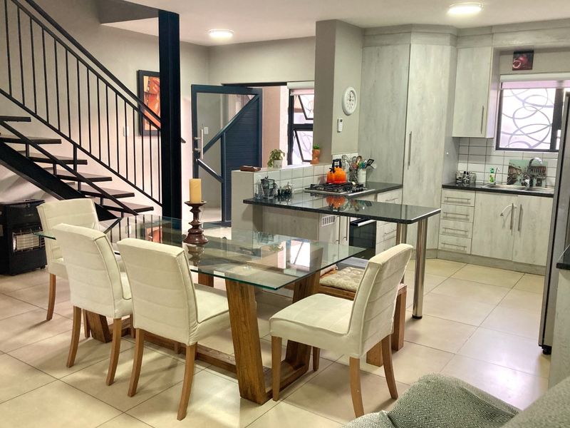 Open-plan living and dining area featuring a modern kitchen with granite countertops, gas hob, and a striking metal staircase leading to the upper level.