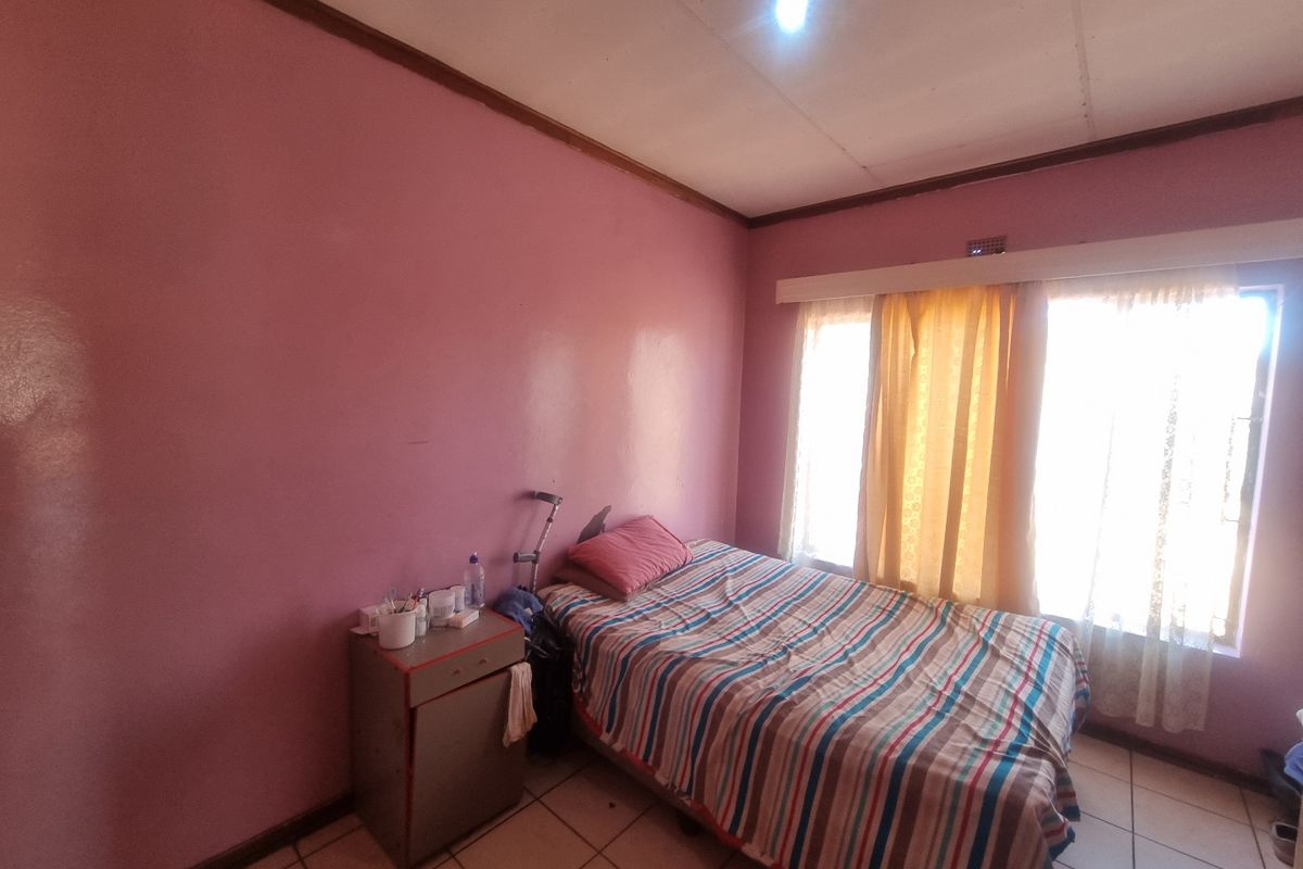 A bedroom featuring tiled flooring and large windows with curtain rails, requiring cosmetic updates to the walls and ceiling.