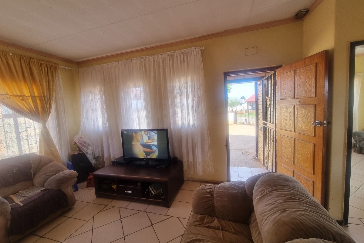 A living room featuring tiled flooring and direct access to the exterior through a timber door with an integrated security gate.