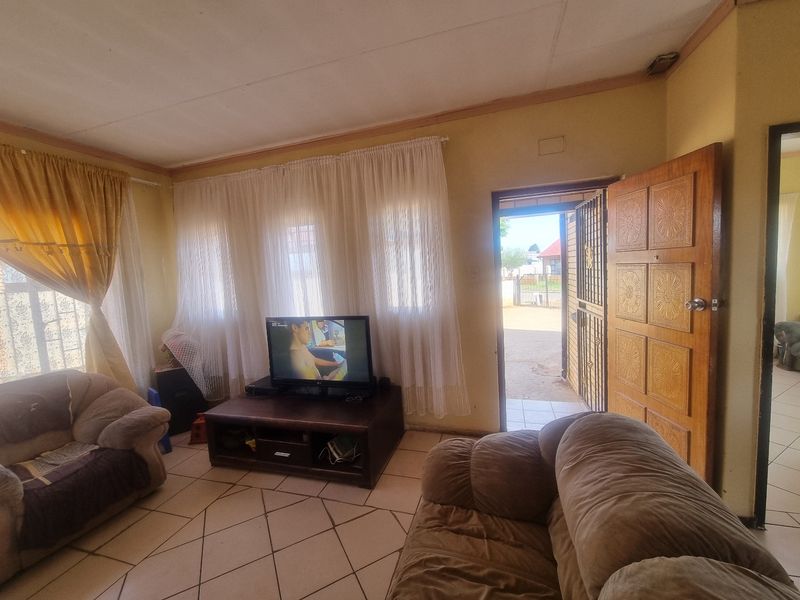 A living room featuring tiled flooring and direct access to the exterior through a timber door with an integrated security gate.