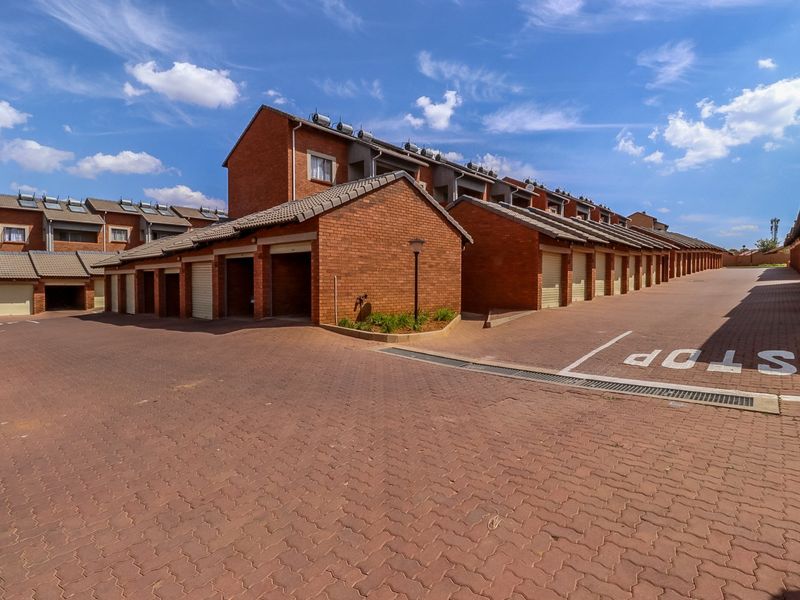 Exterior view of a residential apartment complex featuring multiple garage units, brick construction, and paved driveway access.