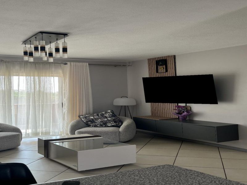 A bright and spacious living room featuring tiled flooring, a decorative feature wall, and a large sliding glass door leading to an outdoor area.