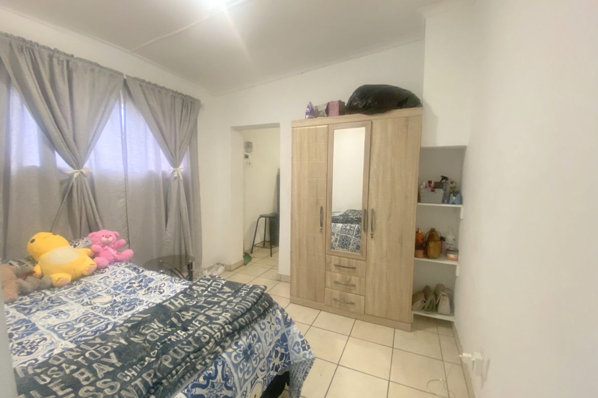 A bedroom featuring tiled flooring and built-in shelving, offering a functional space with neutral wall finishes.