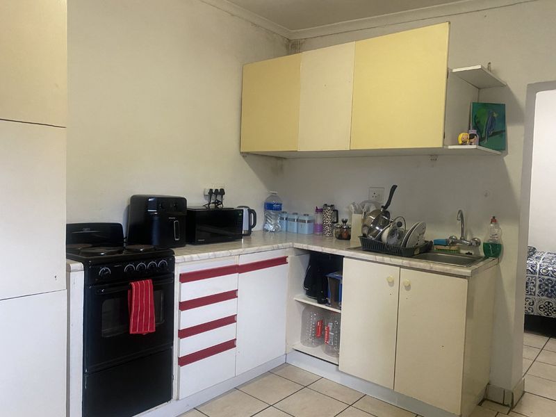 A compact kitchen featuring laminate countertops, built-in cabinetry, and a tiled floor, currently showing signs of wear and requiring cosmetic updates.