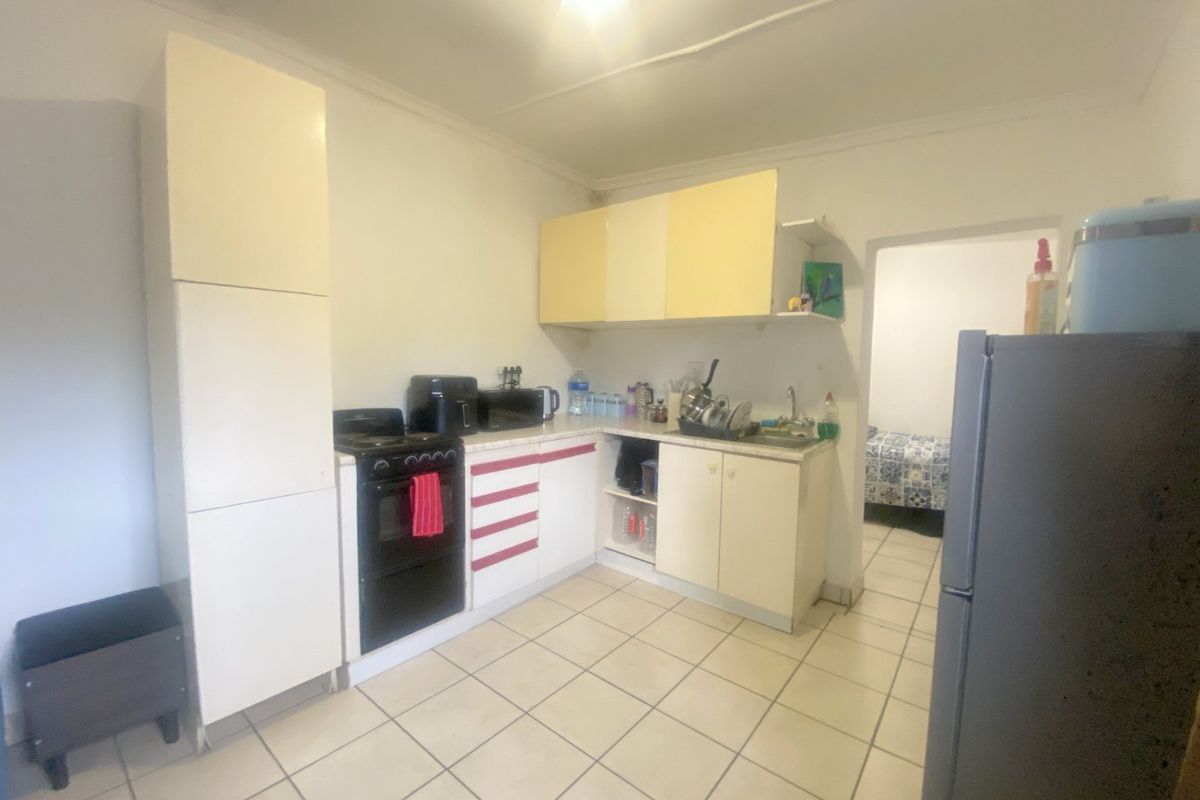 A functional kitchen featuring tiled flooring, built-in cabinetry, and a freestanding stove, offering potential for modernization and aesthetic updates.