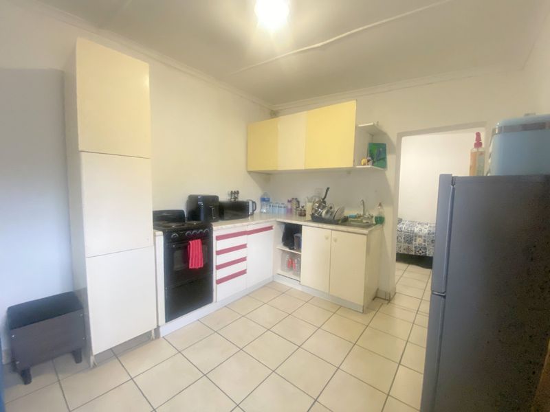 A functional kitchen featuring tiled flooring, built-in cabinetry, and a freestanding stove, offering potential for modernization and aesthetic updates.