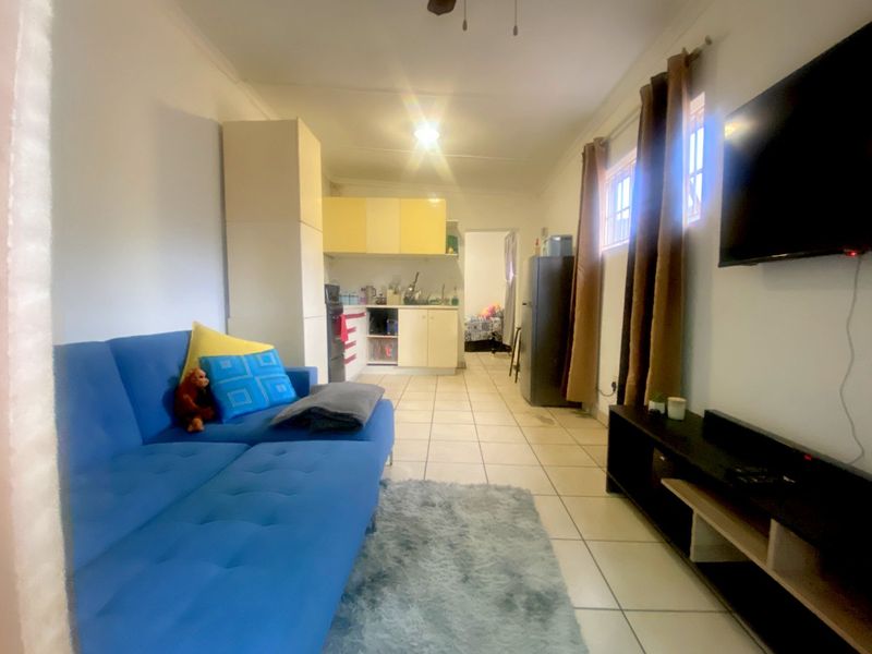 Open plan living area featuring tiled flooring and a compact kitchen with built-in cabinetry, creating a functional combined living and cooking space.