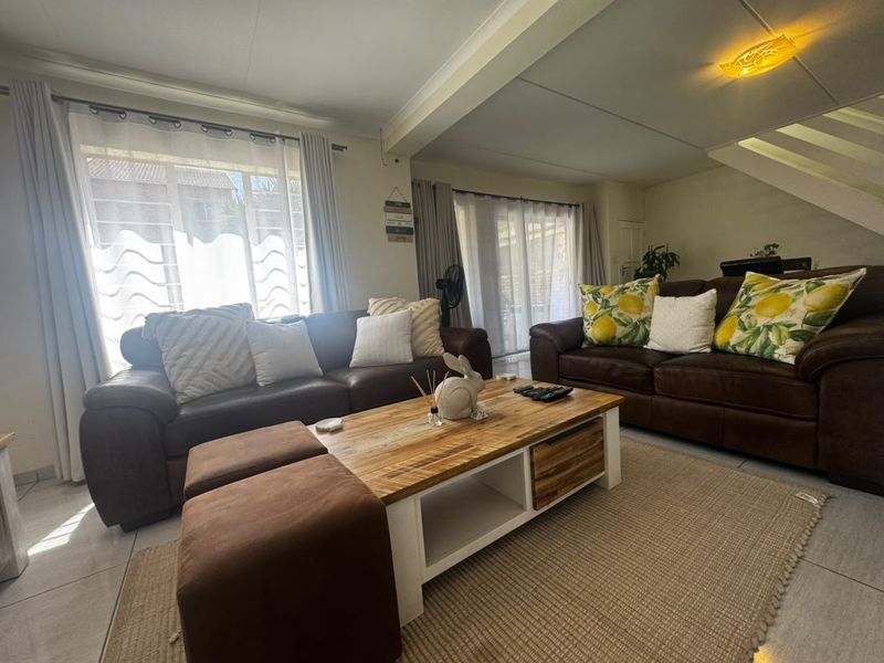 A comfortable living room featuring tiled flooring and large sliding glass doors that provide ample natural light.