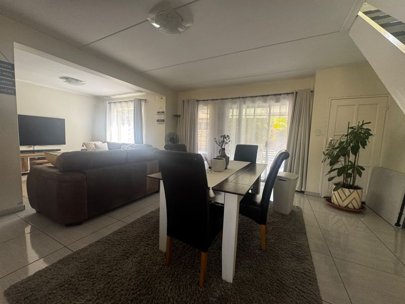 Spacious open-plan living and dining area featuring tiled flooring, neutral walls, and sliding glass doors providing access to the outdoor space.